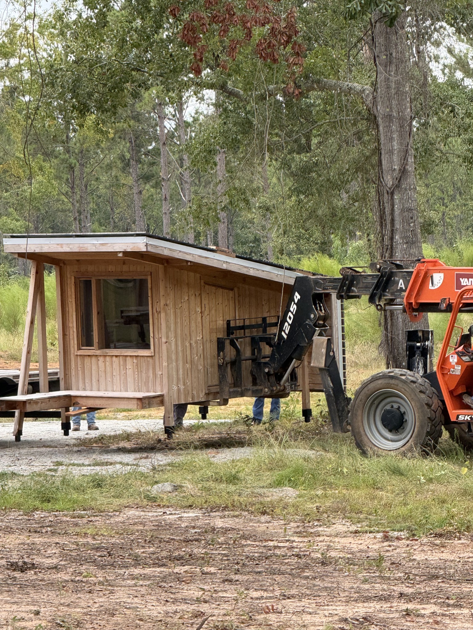 Timber cabin being positioned among mature trees with lifting equipment