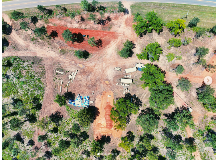 Aerial view of a wooded development site with access paths, cleared areas, and structures